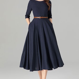 May include: A navy blue midi dress with a boat neckline and a brown belt. The dress has a full skirt and pockets on the sides.