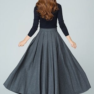 May include: A gray pleated maxi skirt with a high waistline. The skirt is made of a soft, flowing fabric and has a full, A-line silhouette.