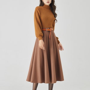May include: A woman is wearing a brown turtleneck sweater with a brown skirt and a brown leather belt. She is wearing black tights and black heels.