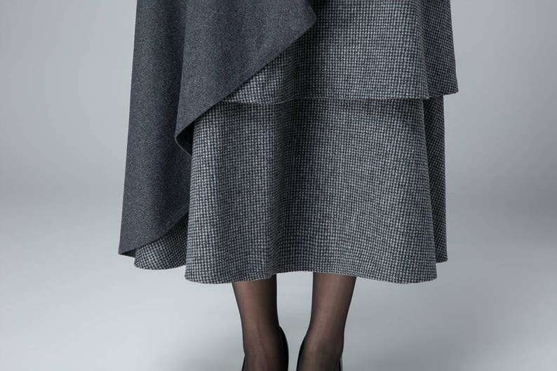 May include: A gray and white plaid skirt with a gray overlay. The skirt is knee-length and has a flowy silhouette.