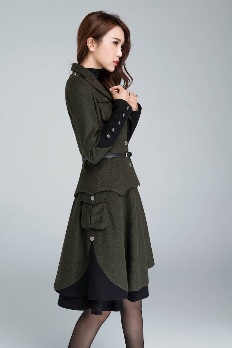 Puede incluir: Una chaqueta de lana verde con ribetes negros en las mangas y una falda a juego. La chaqueta tiene un cintur&oacute;n y un bolsillo grande en la falda.