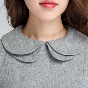 Puede incluir: Un vestido de lana gris con un cuello Peter Pan. El cuello tiene tres capas y es de un tono de gris m&aacute;s claro que el vestido.