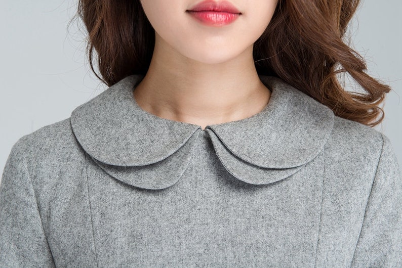 Puede incluir: Un vestido de lana gris con un cuello Peter Pan. El cuello tiene tres capas y es de un tono de gris m&aacute;s claro que el vestido.