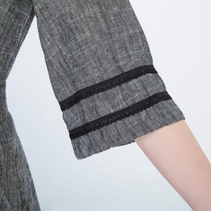 May include: Close-up of a gray linen dress with black lace trim on the sleeves.