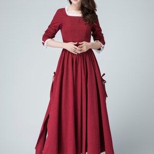 May include: A long, red dress with a white lace trim around the neckline and cuffs. The dress has a gathered skirt and a white underskirt.