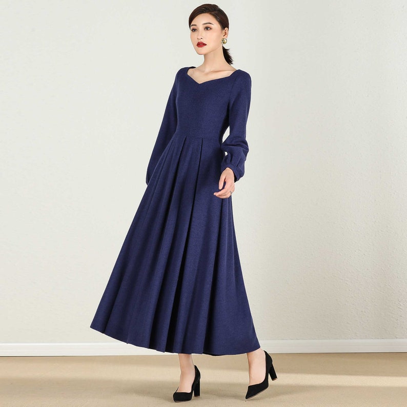 May include: A long-sleeved, navy blue dress with a sweetheart neckline and a gathered skirt. The dress has long, puffed sleeves and a fitted bodice.