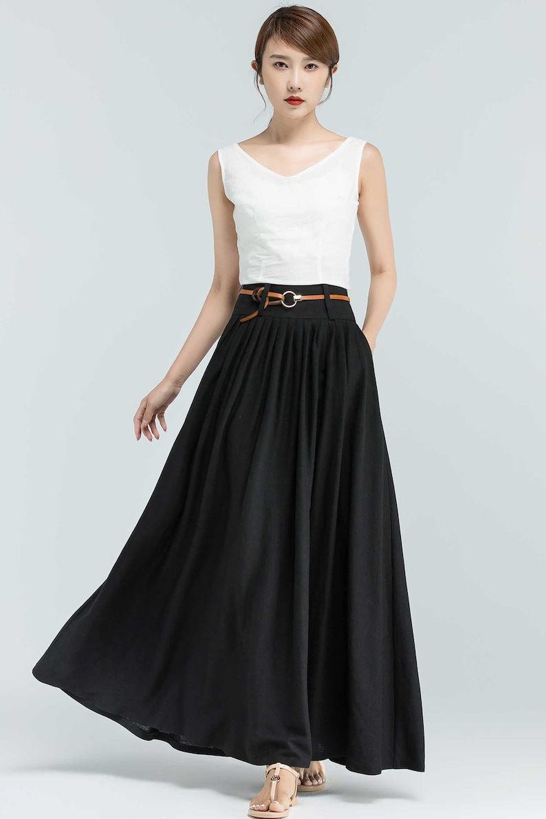 May include: A black maxi skirt with a brown leather belt and a silver buckle. The skirt has pleats and is made of a lightweight fabric.