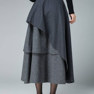 May include: A gray midi skirt with a layered design. The skirt has a solid gray top layer and a checkered bottom layer.