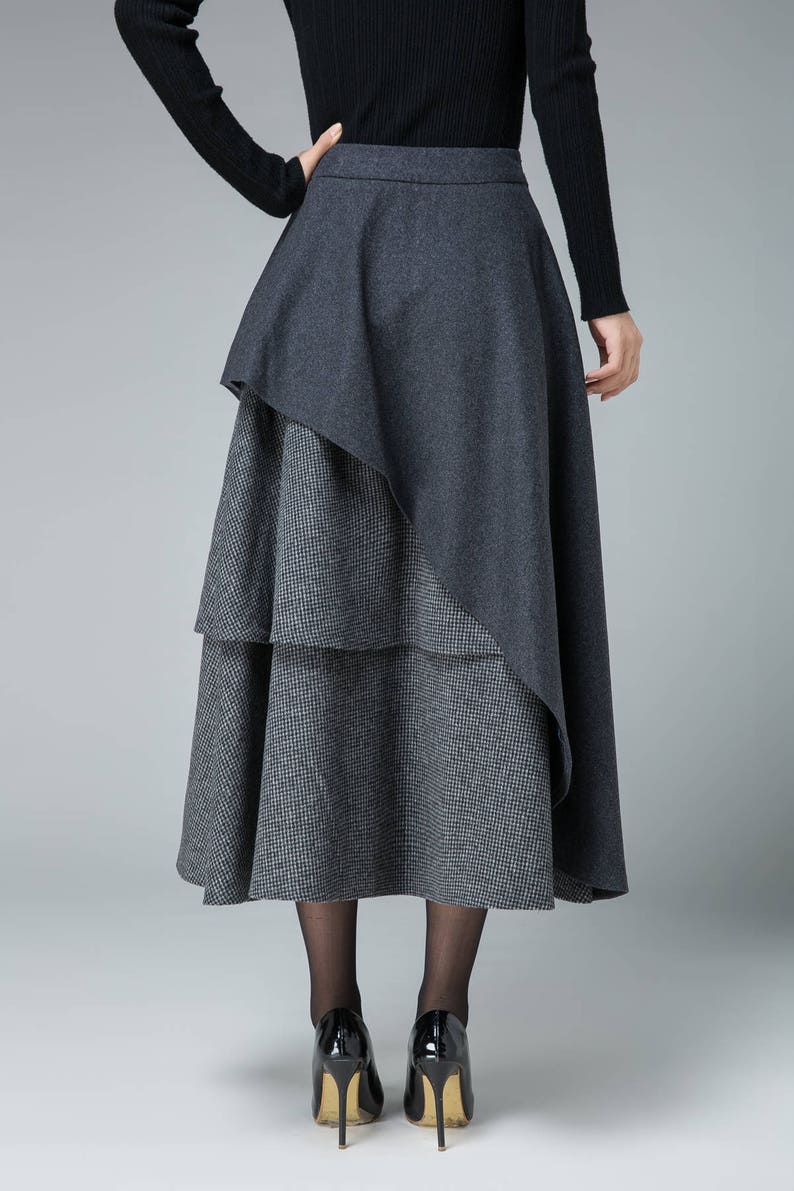 May include: A gray midi skirt with a layered design. The skirt has a solid gray top layer and a checkered bottom layer.