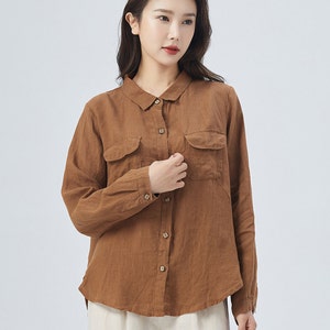 May include: A brown linen shirt with a collared neckline, long sleeves, and two patch pockets on the front. The shirt has a button-up closure.