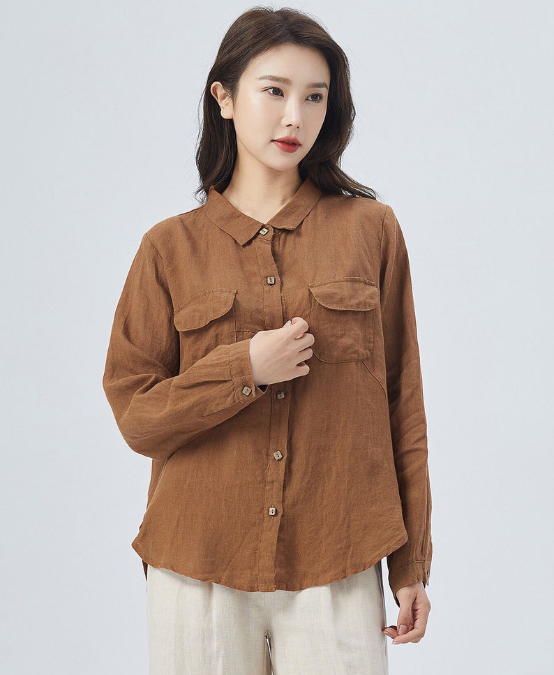 May include: A brown linen shirt with a collared neckline, long sleeves, and two patch pockets on the front. The shirt has a button-up closure.