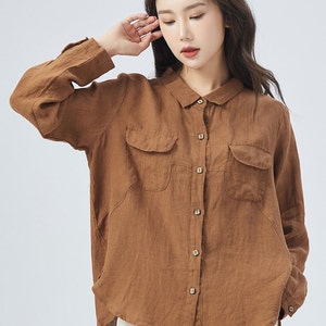 May include: A brown linen shirt with long sleeves, a collared neckline, and two patch pockets on the front. The shirt has a button-up closure.