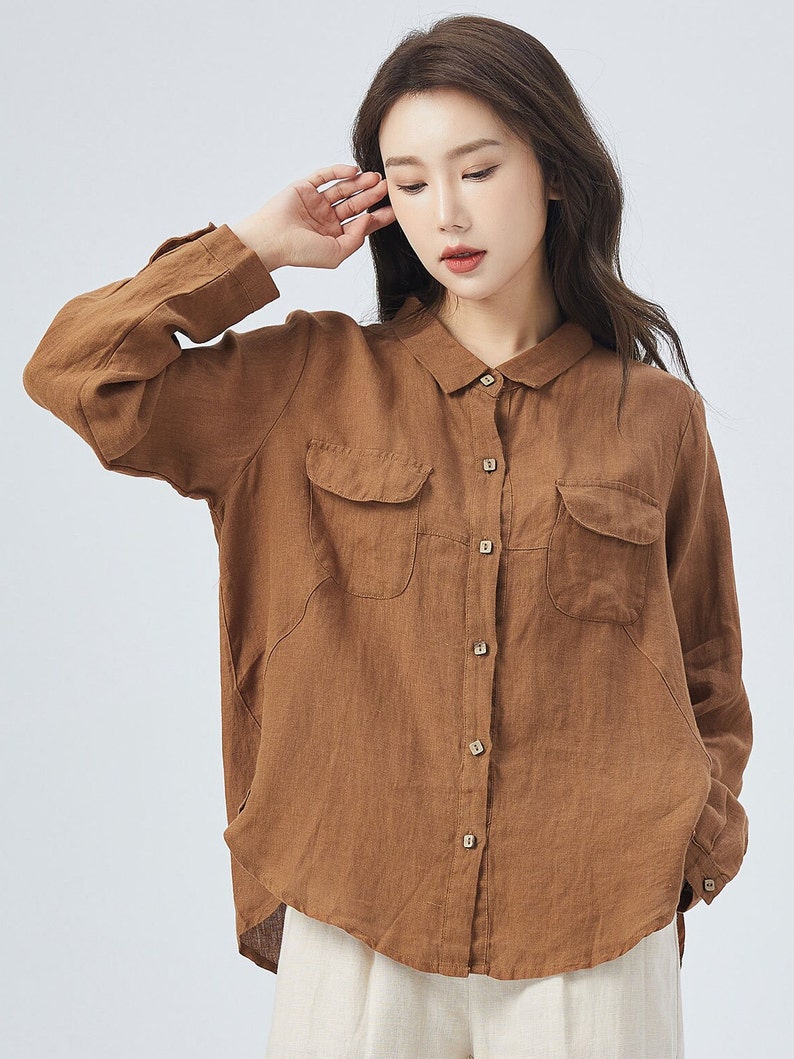 May include: A brown linen shirt with long sleeves, a collared neckline, and two patch pockets on the front. The shirt has a button-up closure.