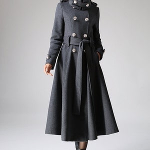 May include: A long, gray wool coat with a high collar, double-breasted closure, and a belt. The coat has a flared skirt and silver buttons.