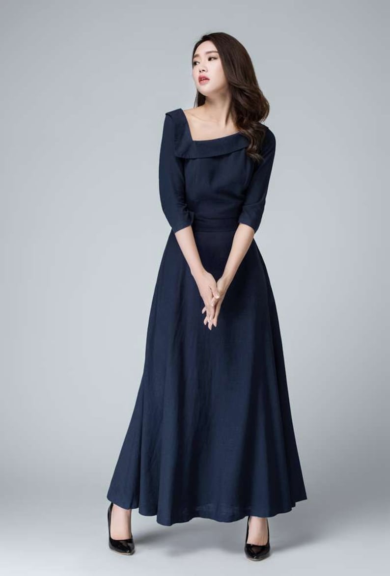 May include: A navy blue maxi dress with a square neckline and three-quarter sleeves. The dress has a fitted bodice and a flowing skirt.