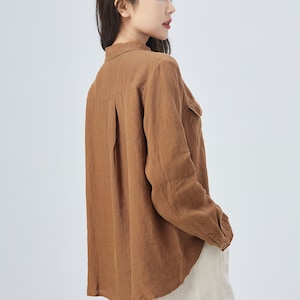 May include: A brown linen shirt with long sleeves and a button-down collar. The shirt has a relaxed fit and a slightly curved hem.