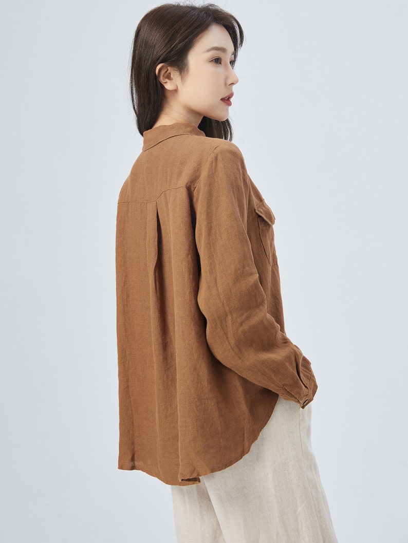 May include: A brown linen shirt with long sleeves and a button-down collar. The shirt has a relaxed fit and a slightly curved hem.