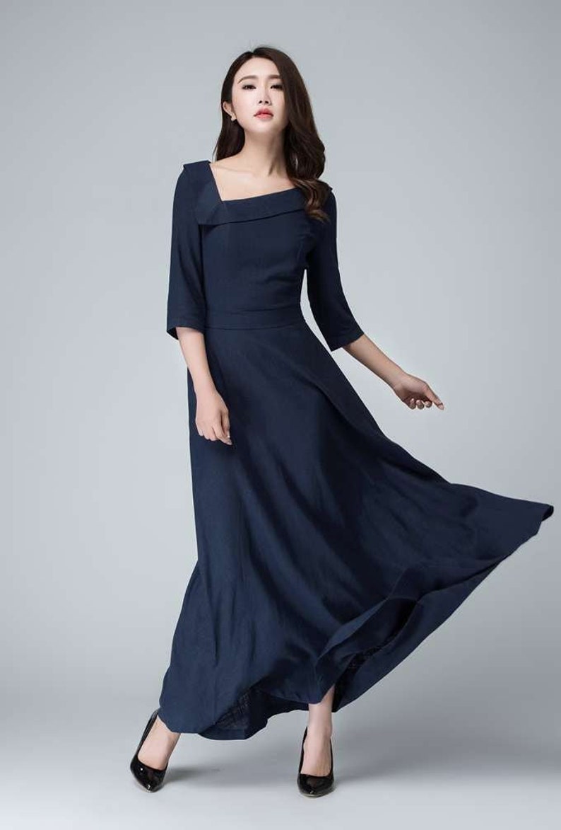 May include: A navy blue maxi dress with a square neckline and 3/4 sleeves. The dress has a fitted bodice and a flowing skirt.