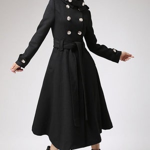 May include: A black double-breasted coat with a high collar and a belt. The coat has a flared skirt and gold buttons.