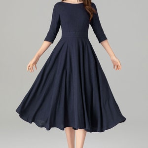 May include: A navy blue midi dress with a boat neck and 3/4 sleeves. The dress has a fitted bodice and a full skirt.