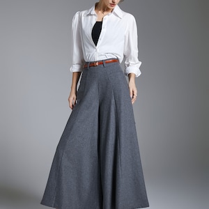 May include: A woman wearing a white button-down shirt with a brown belt and gray wide-leg pants.