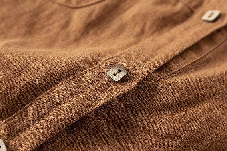 May include: Close-up of a brown linen shirt with a wooden button.