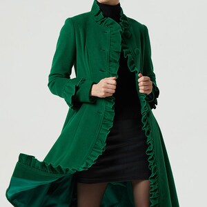 May include: A long, emerald green coat with a ruffled collar, cuffs, and hem. The coat has a button closure and is made of a soft, luxurious fabric.