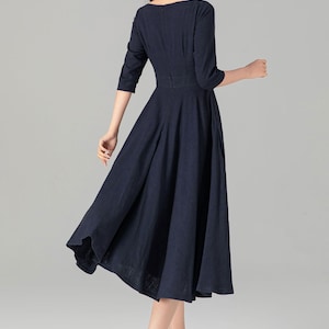 May include: A navy blue midi dress with a boat neckline and a fitted bodice. The dress has a full skirt and is made of a lightweight fabric.