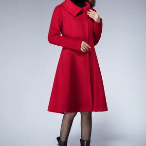 May include: A red wool coat with a wide collar and a flared skirt. The coat is knee-length and has a single button closure.