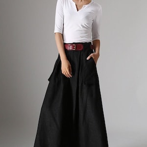 May include: A black maxi skirt with a wide red belt and two large pockets on the front. The skirt is made of a lightweight fabric and has a flowy silhouette.