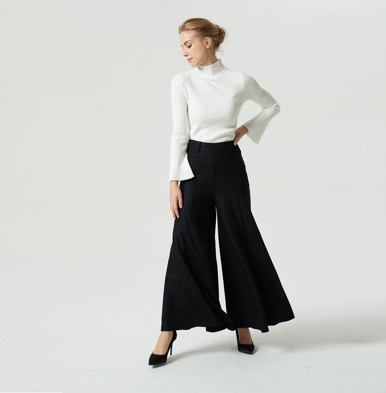 May include: A woman wearing a white turtleneck sweater and black wide-leg pants with a flared hem.