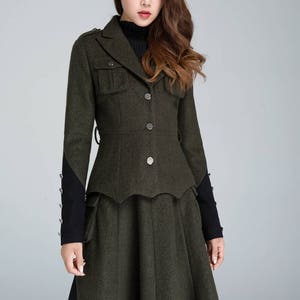 Puede incluir: Un conjunto de chaqueta y falda de lana verde oscuro con un corpi&ntilde;o ajustado y una falda acampanada. La chaqueta tiene cuello, cuatro botones y dos bolsillos de solapa. La falda tiene un dobladillo festoneado.