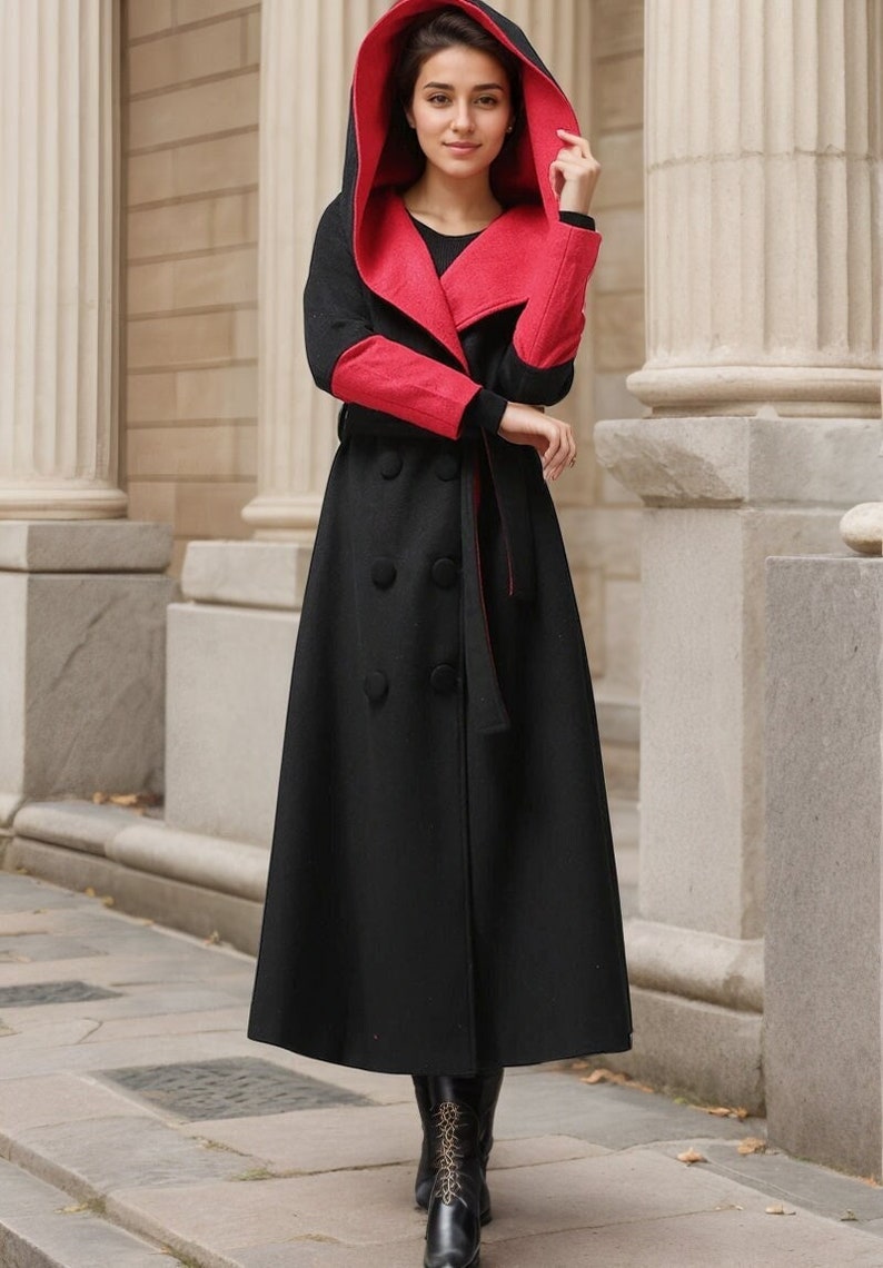 May include: A long black coat with a red hood and red lining. The coat has a belt and a double breasted closure.