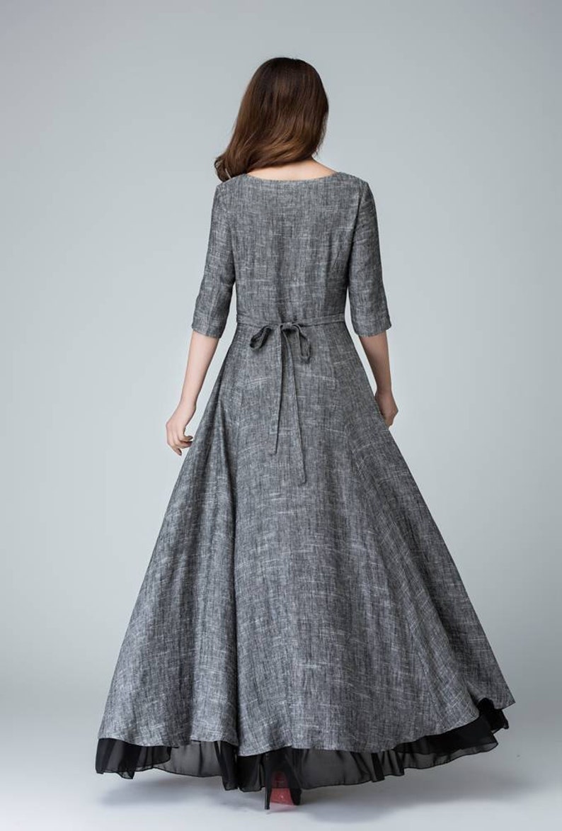 K&ouml;nnte beinhalten: Ein graues Leinen-Maxikleid mit einer Schleife in der Taille und einem schwarzen T&uuml;ll-Unterrock.