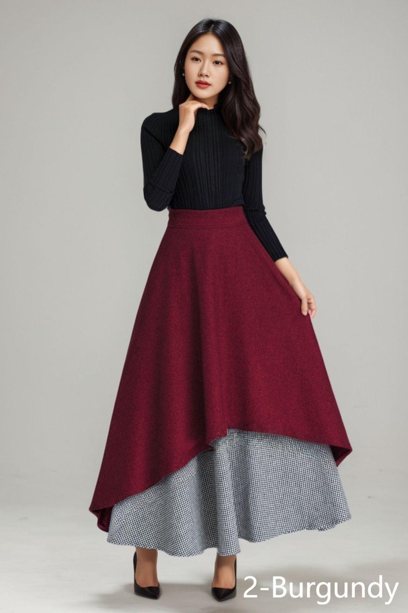 K&ouml;nnte beinhalten: Ein burgunderfarbener und schwarzer Midirock mit hoher Taille und einem geschichteten Design. Der Rock ist aus einem dicken, strukturierten Stoff gefertigt und hat eine leicht ausgestellte Silhouette.