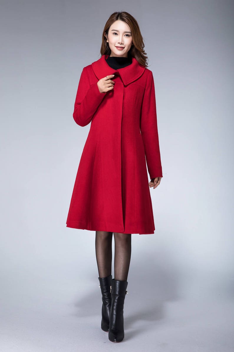 May include: A red wool coat with a wide collar and a flared skirt. The coat is buttoned up the front and has long sleeves.