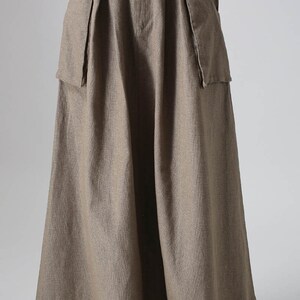 May include: A long, brown, linen skirt with a wide brown leather belt and large pockets on the sides.