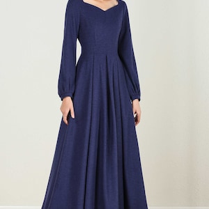 May include: A long-sleeved, navy blue dress with a square neckline and a fitted bodice. The dress has a flowing skirt with pleats and a slightly puffed sleeve.