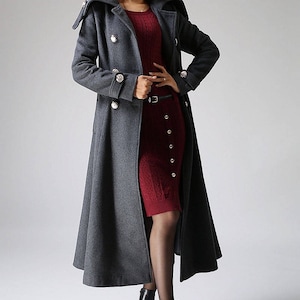 May include: A long, gray wool coat with a double-breasted closure and large buttons. The coat has a wide collar and a flared skirt.