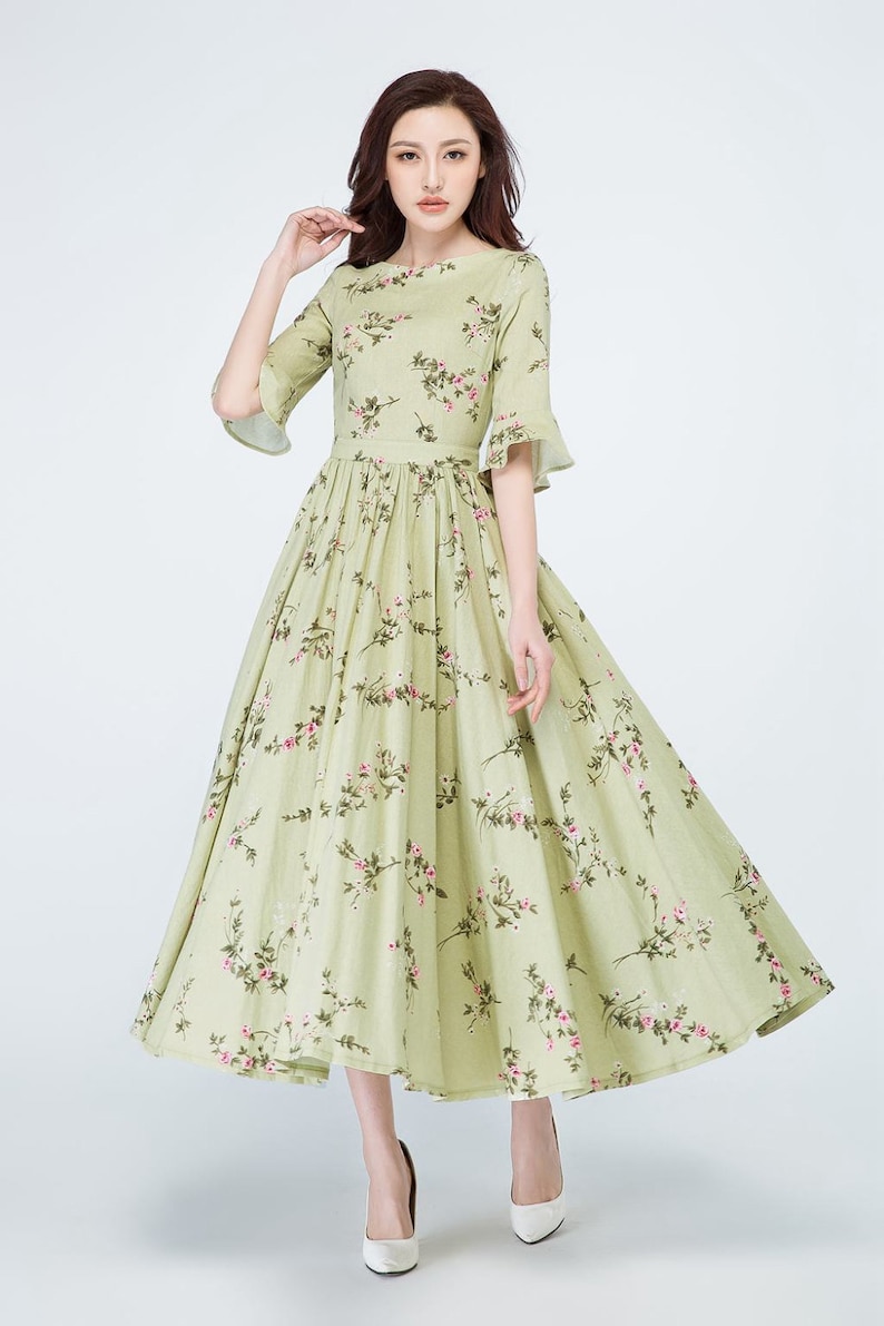 Peut inclure: Une robe vert clair &agrave; imprim&eacute; floral, avec un col rond et des manches courtes &eacute;vas&eacute;es. La robe pr&eacute;sente un corsage ajust&eacute; et une jupe longue et fluide. Le motif floral comprend des fleurs roses et des feuilles vertes.