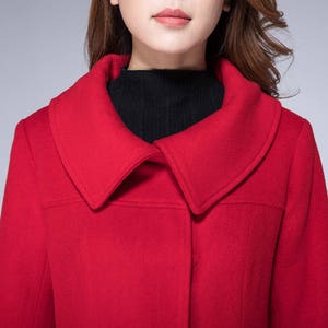 May include: A red wool coat with a large, wide collar. The coat has a single button closure at the front.