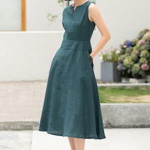 Peut inclure: Une femme portant une robe midi sans manches bleu sarcelle avec un d&eacute;collet&eacute; en V. La robe a un corsage ajust&eacute; et une jupe ample.