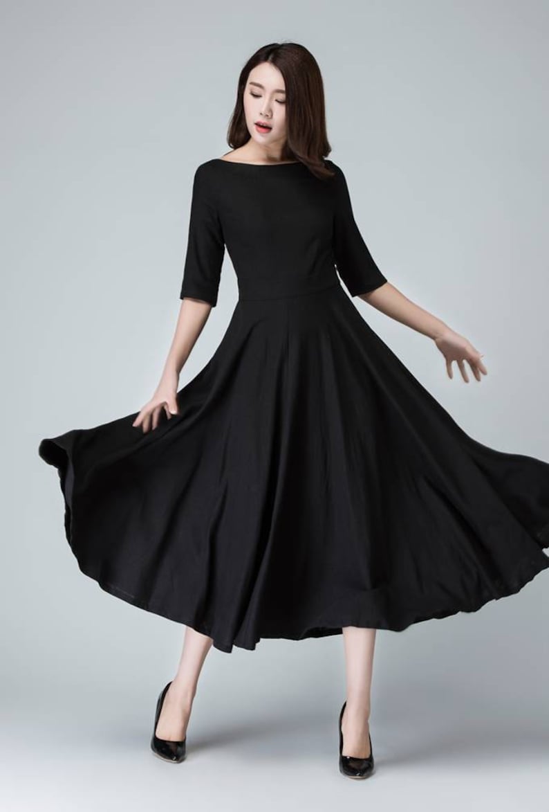 Może przedstawiać: Czarna sukienka midi z dekoltem ł&oacute;dkowym i szeroką sp&oacute;dnicą. Sukienka jest wykonana z lekkiej tkaniny i ma luźny kr&oacute;j.