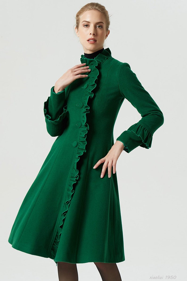May include: A green wool coat with a ruffled collar and cuffs. The coat has a fitted bodice and a flared skirt.