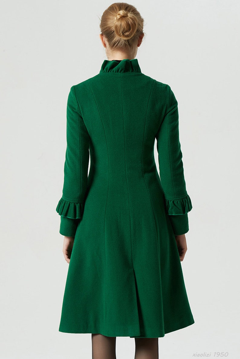 May include: A long, green coat with a ruffled collar and cuffs. The coat has a fitted bodice and a flared skirt.