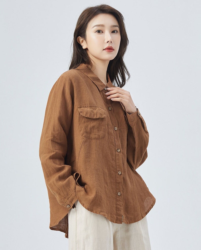 May include: A brown linen shirt with a button-down front and a single chest pocket. The shirt has long sleeves and a relaxed fit.