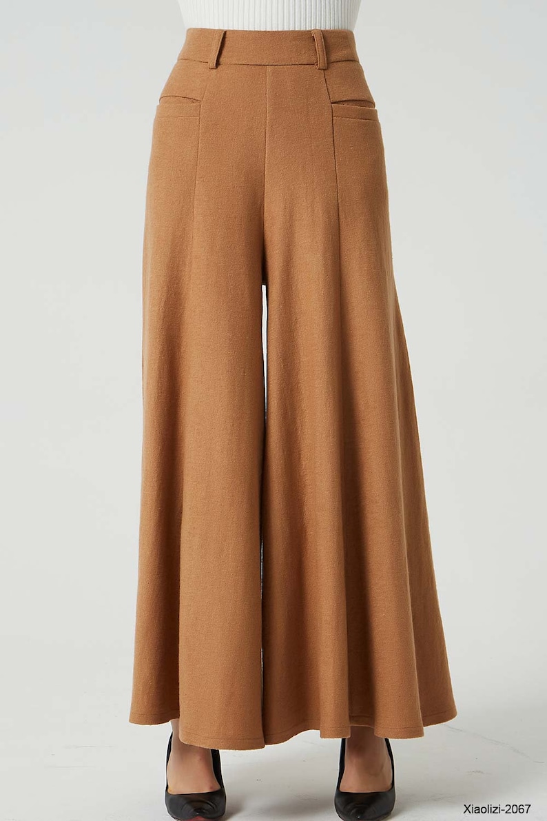 May include: Wide-leg, high-waisted pants in a brown color. The pants have a relaxed fit and a flowing silhouette.