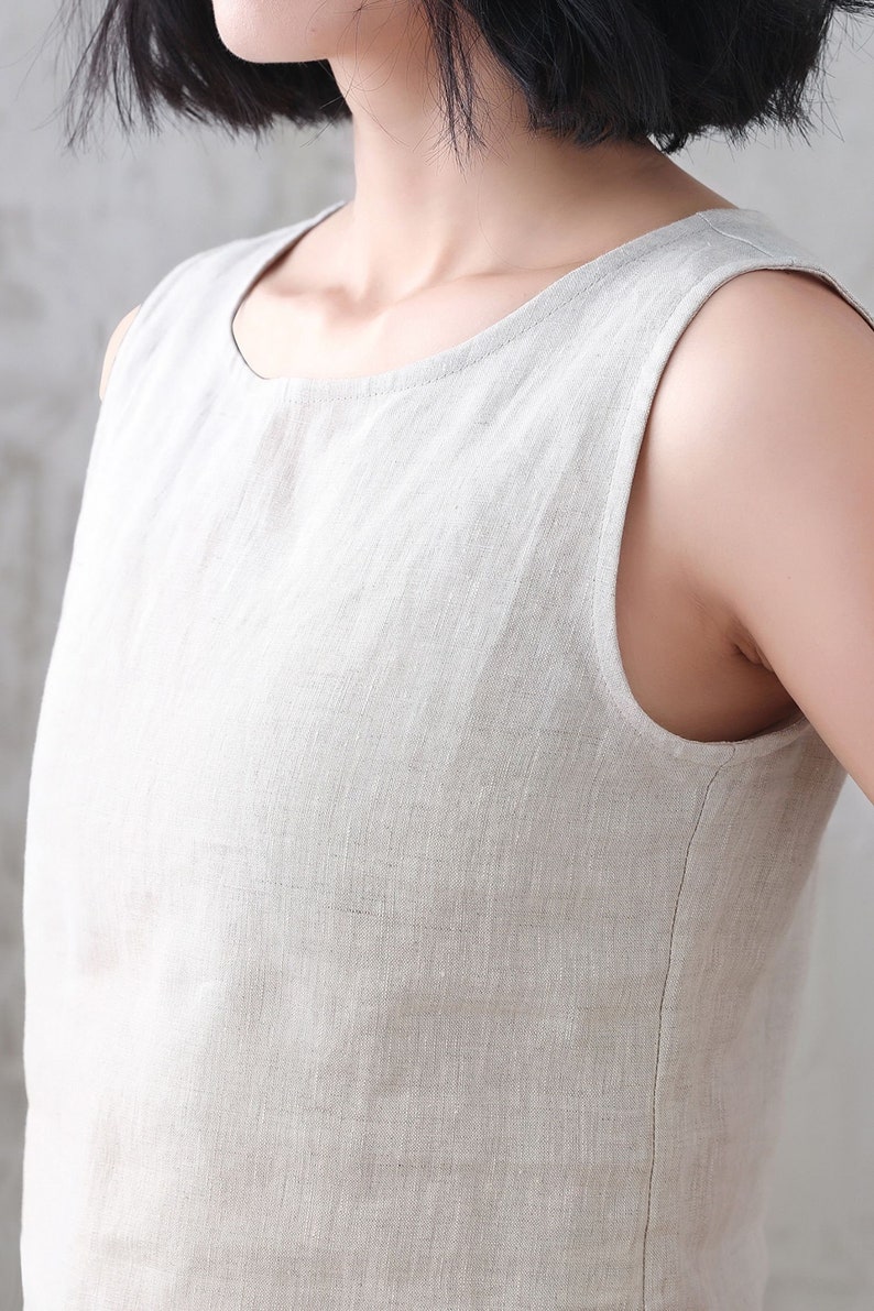 Pu&ograve; includere: Un abito in lino senza maniche di colore beige chiaro. L'abito ha una scollatura rotonda e una vestibilit&agrave; rilassata.