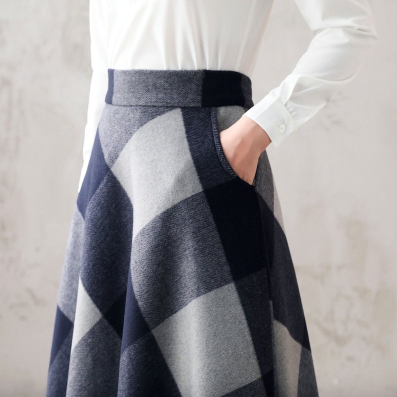 May include: A gray and navy blue plaid skirt with a flared silhouette. The skirt has a pocket on the right side.