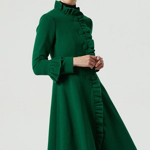May include: A green wool coat with a ruffled collar and cuffs. The coat has a fitted bodice and a flared skirt.